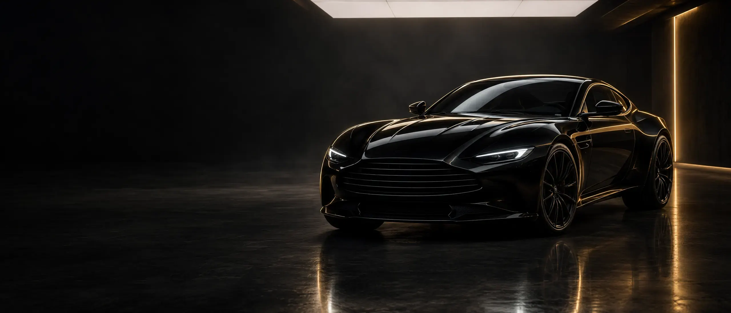 Black luxury sports coupe with gold rim lighting in a dark detailing studio